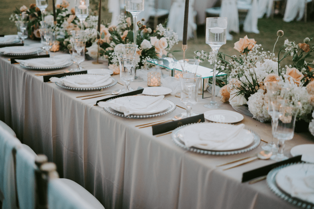 A beautifully arranged table featuring white and gold linens, adorned with elegant floral centerpieces.