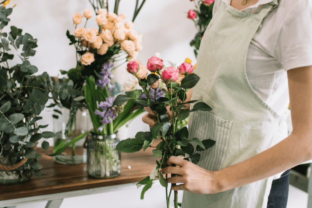 A woman smiles holding a vibrant bouquet of flowers in her hands, showcasing a variety of colors and blooms.